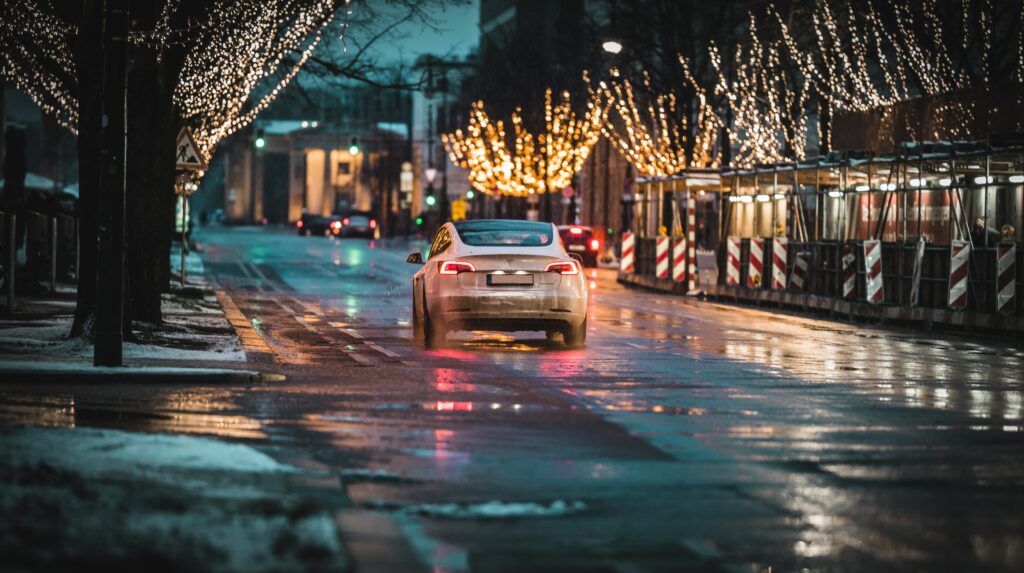 White Tesla driving down the street with multiple lights around.